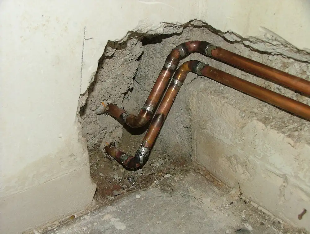 Tuberías de cobre al descubierto en una pared abierta para reparar una fuga