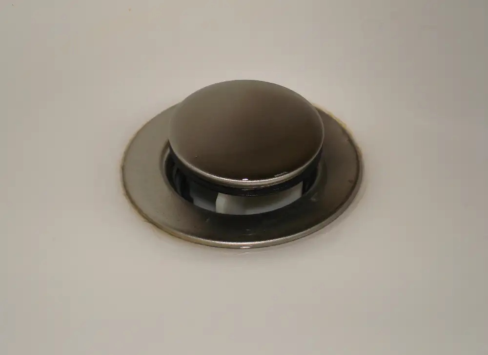Tapón metálico de un desagüe de lavabo, levantado sobre su válvula