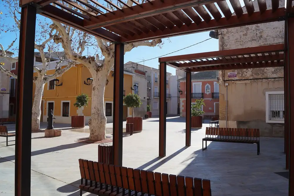 Plaza de San Juan de Aspe, con plataneros, pérgolas de madera y casas de dos plantas